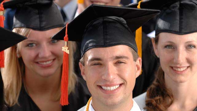 Graduate students wearing mortarboards smile